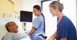 photo of two nurses treating a patient in bed