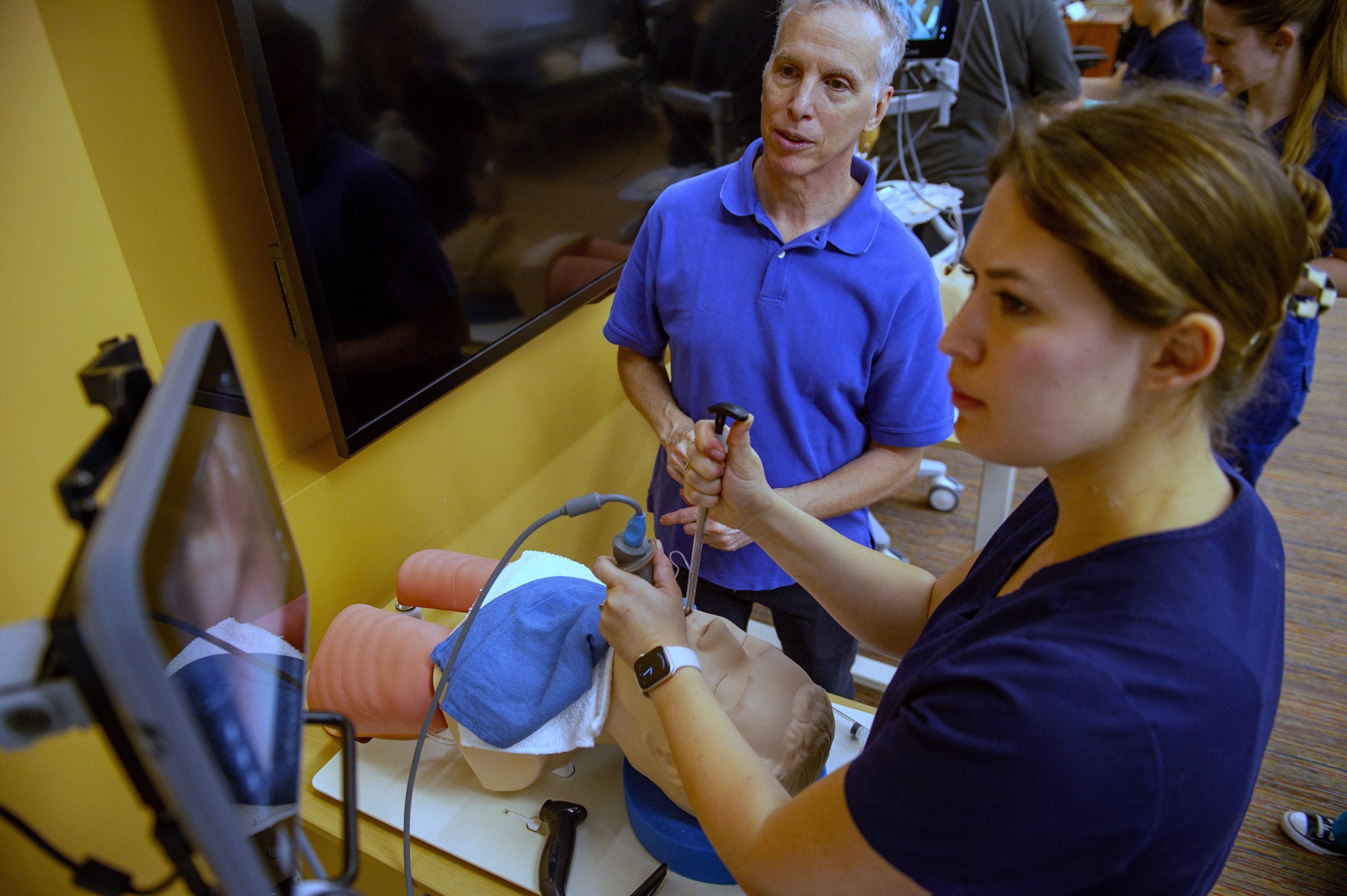 Instructor guides female nursing through training procedure