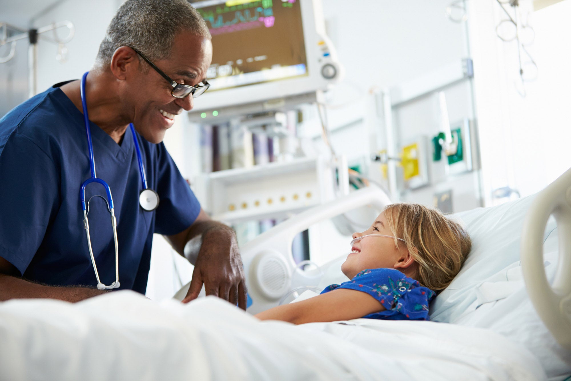 Young Girl Talking To Happy Smiling Male Nurse In Intensive Care Unit
