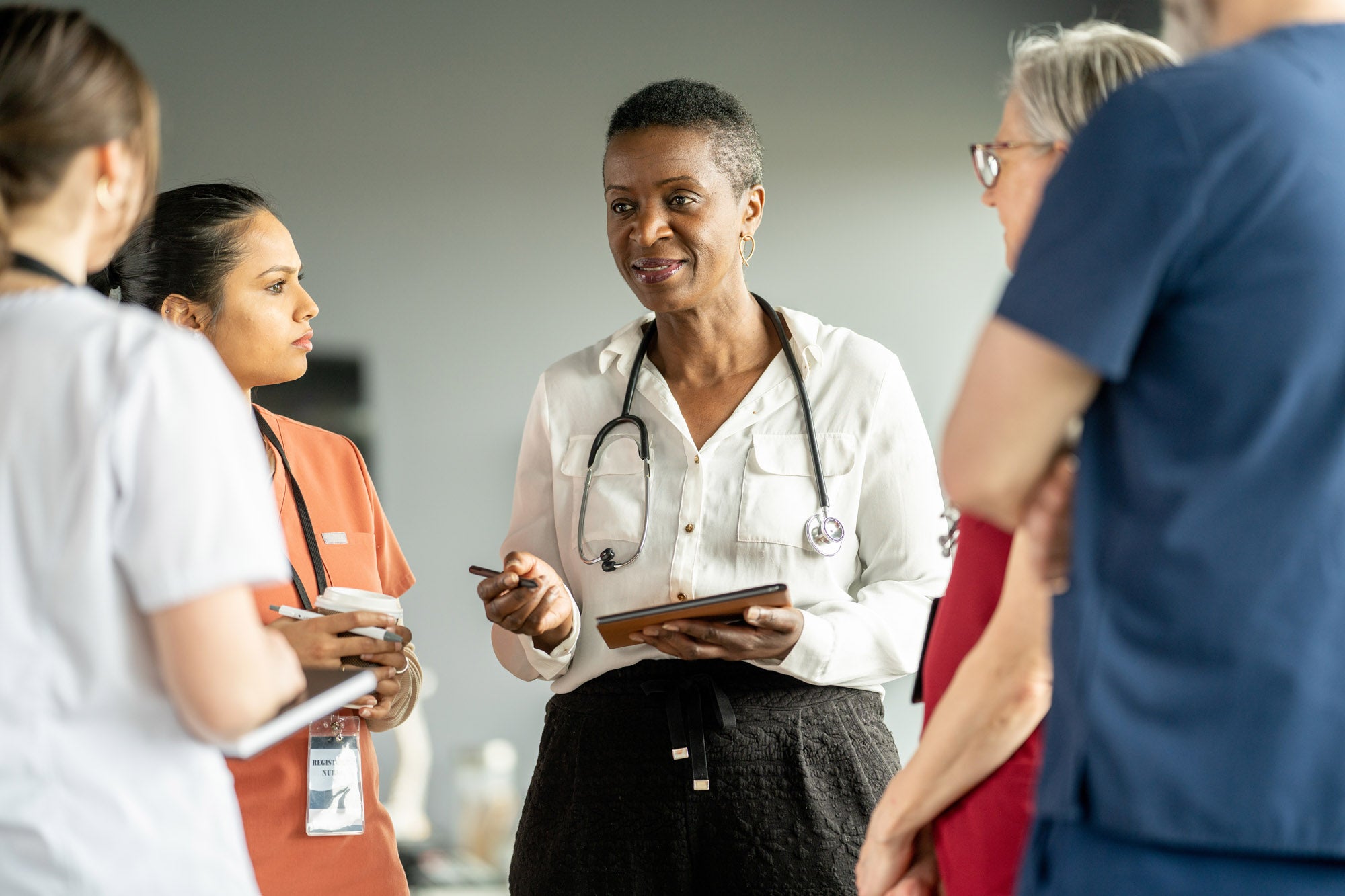 A group of healthcare professionals engaged in a conversation within a hospital environment, discussing patient care and collaboration. The composition conveys teamwork, professionalism, and the dedication of the medical field.