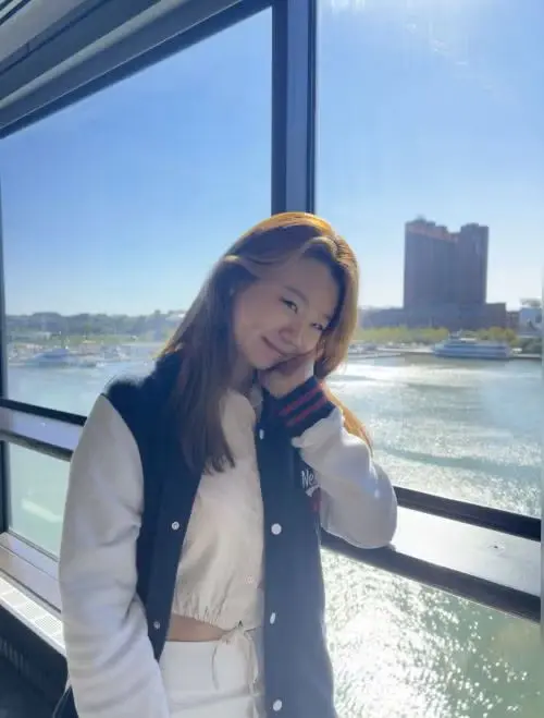 Photo of Michelle Chung on a boat with water and the shoreline behind her